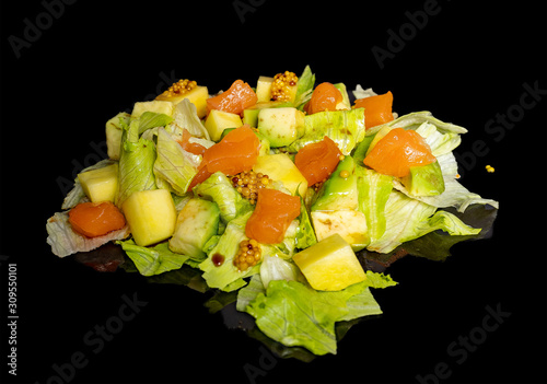 Salad, fish and cheese with sauce on a black background