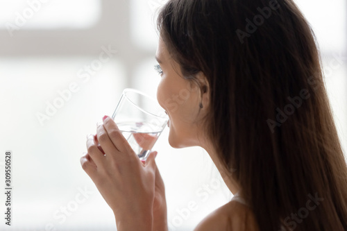 Young woman in bed drink pure water in morning
