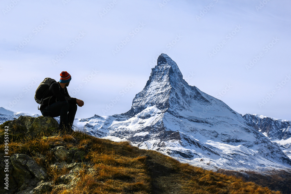 Matterhorn, Switzerland - October 16.2016: A young hiker taking a rest during trekking with the Matterhorn peak at the background. Matterhorn is an attraction in the Swiss alps.