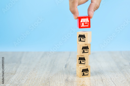 Franchise business,Businessman hand choose reg color wooden toy blog stacked with franchise marketing icons Store.