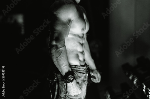 Muscular male torso on black background. Selective focus. Strong abs, bodybuilder man. Black and white. Closeup.