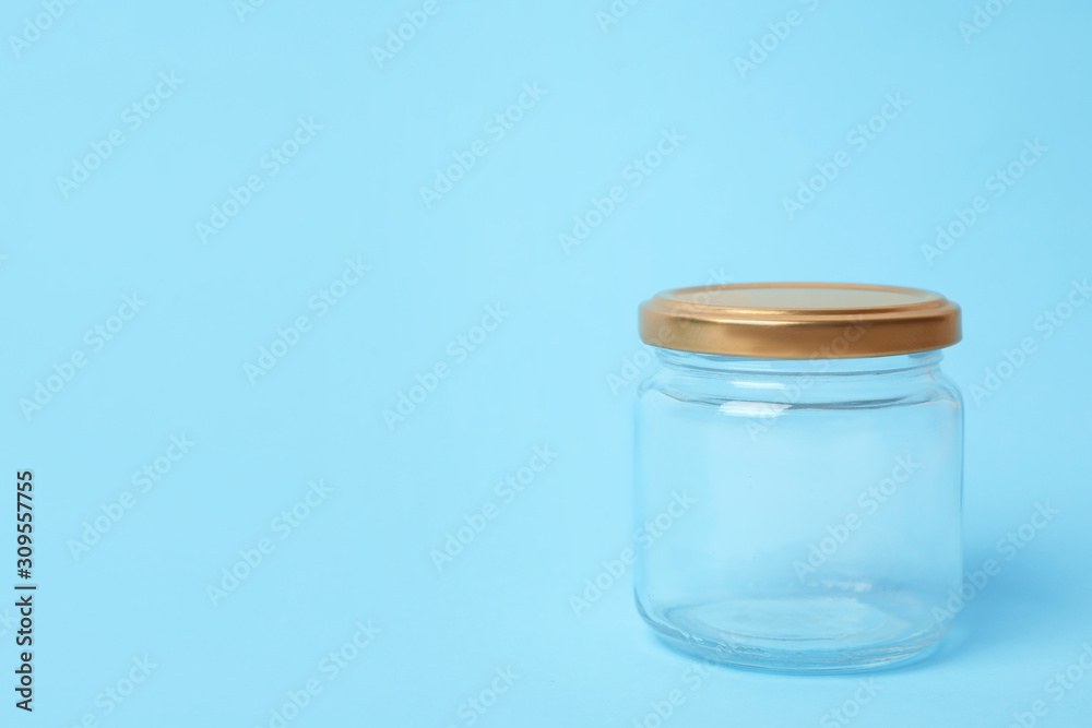 Closed empty glass jar on light blue background, space for text Closed empty glass jar on light blue background, space for text