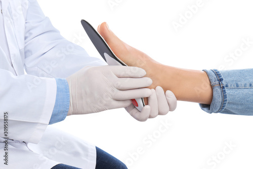 Male orthopedist fitting insole on patient's foot against white background, closeup