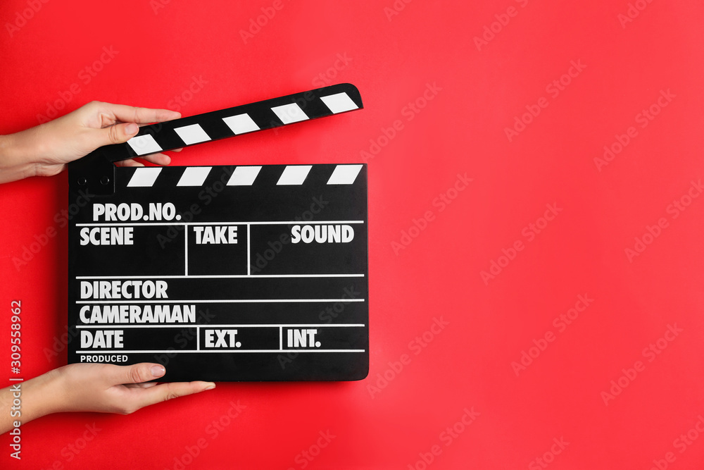 Woman holding clapperboard on red background, closeup with space for text. Cinema production