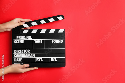 Canvas Print Woman holding clapperboard on red background, closeup with space for text
