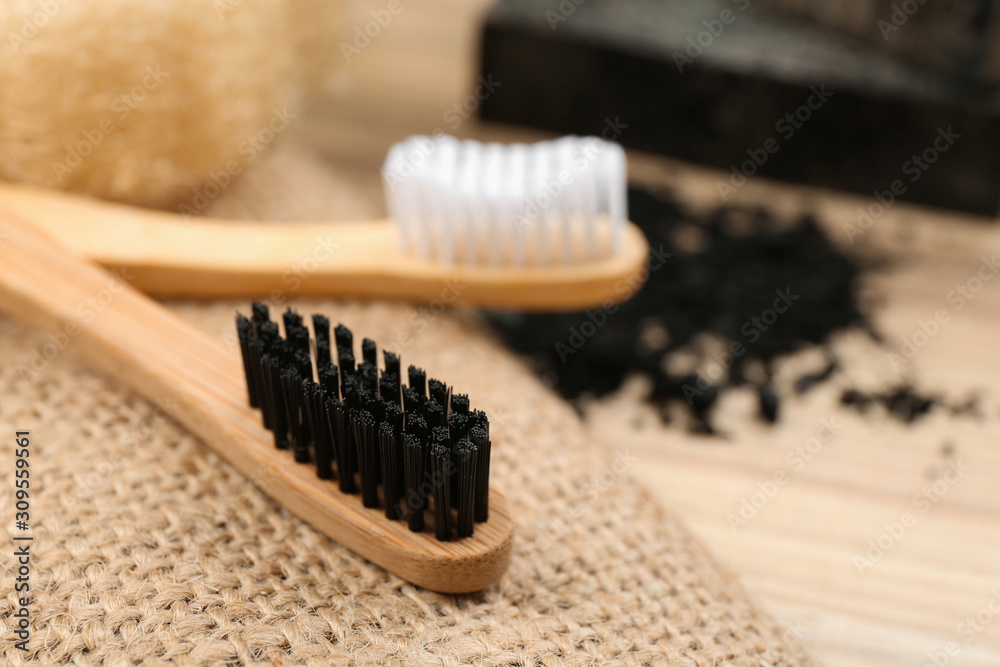 Natural bamboo toothbrush with charcoal bristle on table, closeup Natural bamboo toothbrush with charcoal bristle on table, closeup