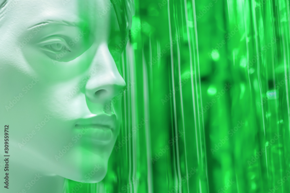 stylish mannequin female woman head close up on warm on bright green blurred background. art concept for advertising and layouts. Copyspace