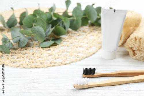 Bamboo toothbrushes on white wooden table. Space for text