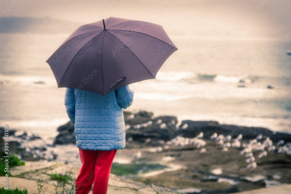 woman with umbrella walking along the coast