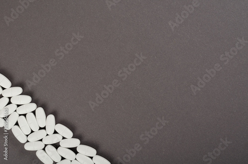 White medical pills composition on dark background.