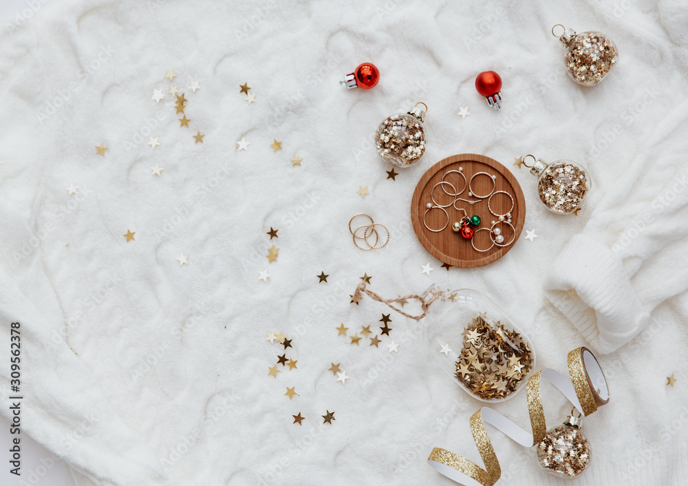 Woman accessories, christmas decorations over oversize warm sweater. Minimal blogger background, flat lay