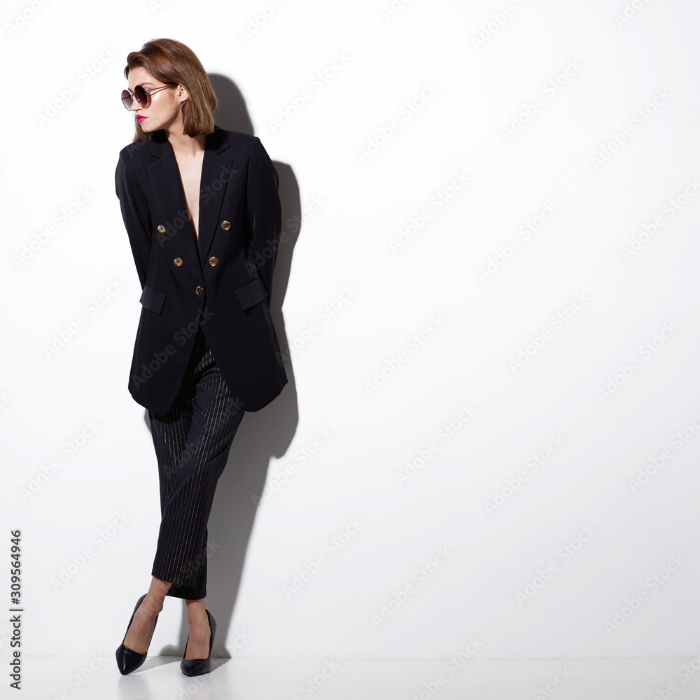 High fashion portrait of young elegant woman. Sunglasses, black jacket, pants. High fashion portrait of young elegant woman. Sunglasses, black jacket, pants.