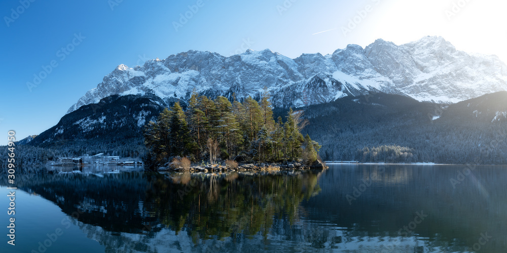 Naklejka premium Beautiful winter day with clear blue sky at the eibsee in south germany with view of the Zugspitze, highest german mountain, island Maximiliansinsel in the front