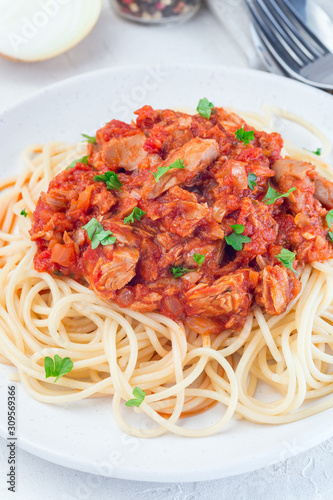 Spaghetti with tuna and tomato basil sauce garnished with parsley, vertical, closeup