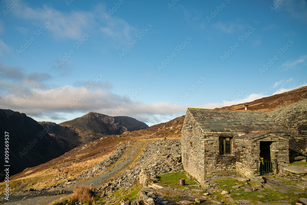 Autumn Fall landscape image of old bothy in Lake Districtr mountains near Buttermere with Haystacks and High Stiel in the distance