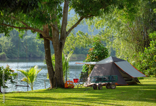 Outdoors and adventure concept. Camping tent in forest near lake.