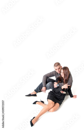 Beautiful young guy and girl sitting and hugging on a white background, top view. Copy space.