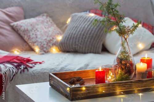 Composition of candles with juniper in vase on  white table agai