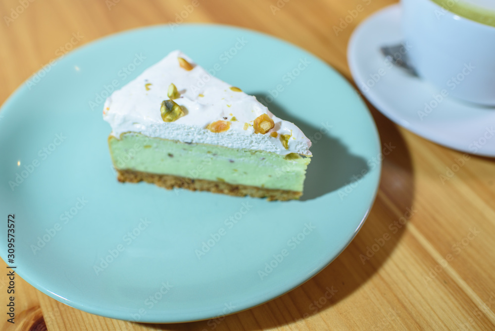 Matcha latte and pistachio cheesecake on a large bright wooden table Matcha latte and pistachio cheesecake on a large bright wooden table