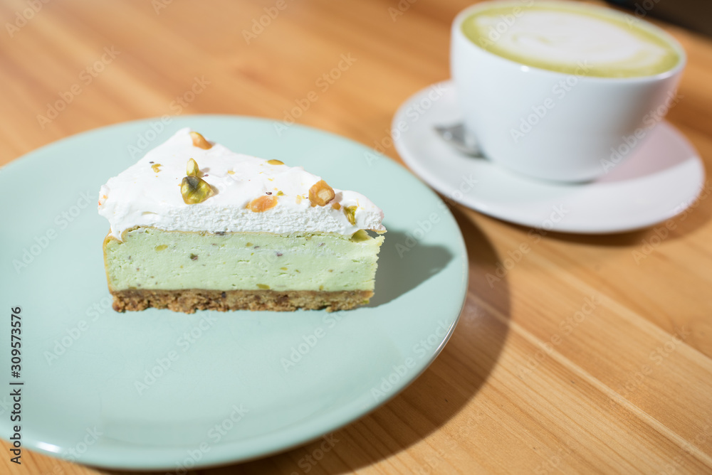 Matcha latte and pistachio cheesecake on a large bright wooden table Matcha latte and pistachio cheesecake on a large bright wooden table