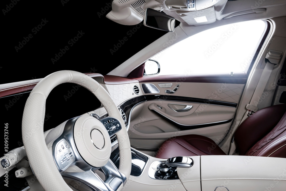Modern luxury car white leather interior with natural wood panel. Part of leather car seat details with stitching. Interior with dashboard. White perforated leather. Car detailing. Car inside