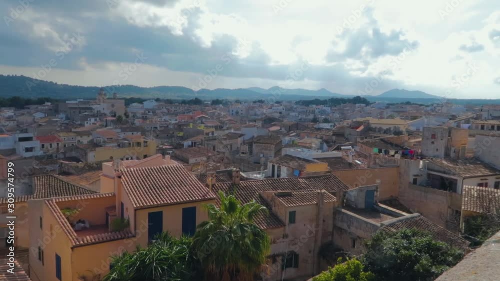 A panning view over the houses of an old town of Capdepera, Mallorca, under the charming cloudy sky. A panning view over the houses of an old town of Capdepera, Mallorca, under the charming cloudy sky.