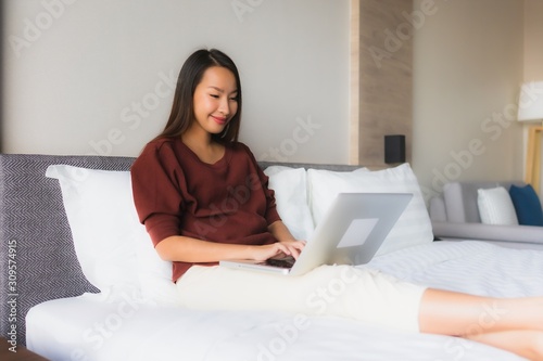 Portrait beautiful young asian women using computer and mobile phone on bed