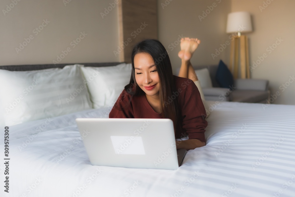 Portrait beautiful young asian women using computer and mobile phone on bed Portrait beautiful young asian women using computer and mobile phone on bed