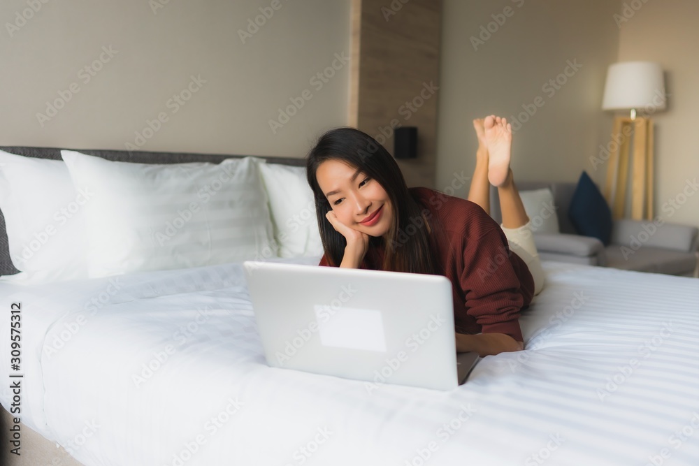 Portrait beautiful young asian women using computer and mobile phone on bed Portrait beautiful young asian women using computer and mobile phone on bed