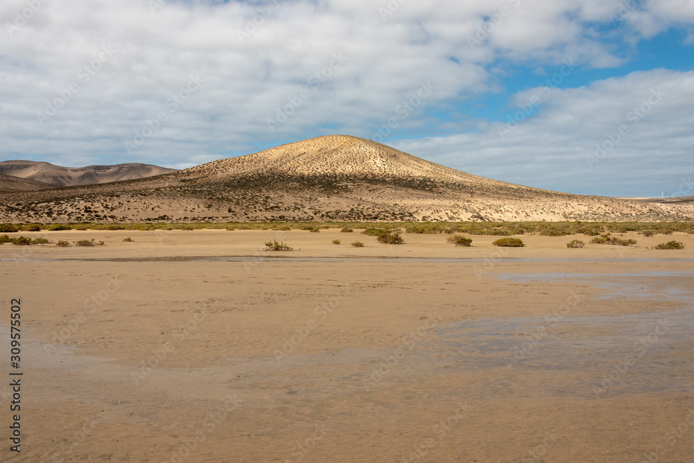 Hills on Playa de Sotavento - wide beach during low tide. Costa Calma, Fuerteventura, Canary Islands, Spain. Hills on Playa de Sotavento - wide beach during low tide. Costa Calma, Fuerteventura, Canary Islands, Spain.