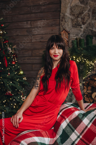 Beautiful young woman in long red dress near the Christmas tree © Iryna