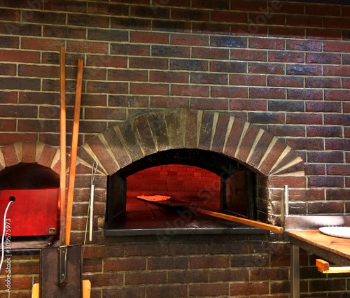 Hot red professional baker oven done with red bricks with a pizza cooking inside of it photo