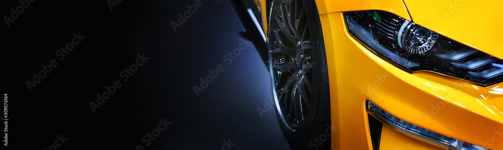 Front headlights of yellow modern car on black background,copy space