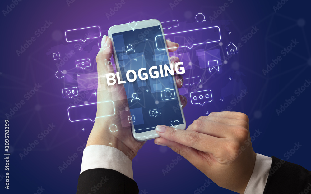 Obraz premium Female hand typing on smartphone with BLOGGING inscription, social media concept