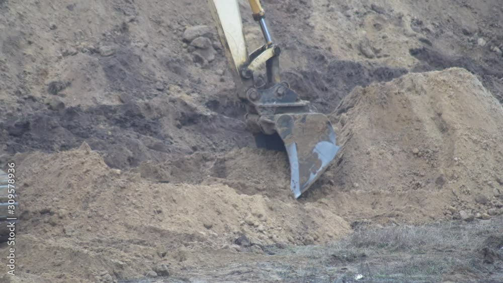 excavator digs a trench. a large bucket rakes the ground from the pit. excavator digs a long pit. overcast weather. the bucket spills out bent near the pit. excavator digs a trench. a large bucket rakes the ground from the pit. excavator digs a long pit. overcast weather. the bucket spills out bent near the pit.