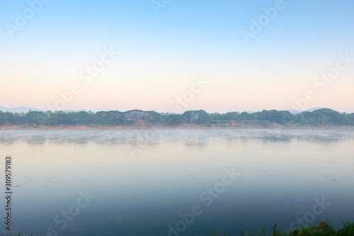 The image is a blurry sky with golden light at morning. The whole area was slightly covered with fog. This image is use as a background image. © stockbob