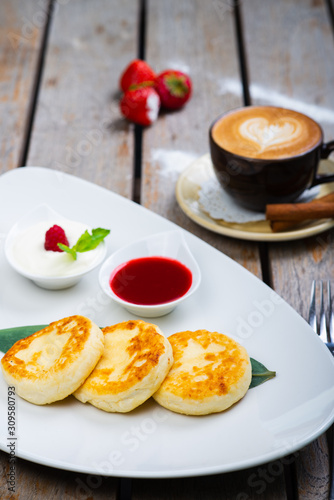Traditional breakfast with coffee and cheesecakes  cottage cheese pancakes on a plate with syrup and jam.