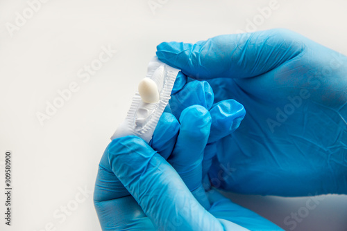 A gloved doctor opens suppositories for anal or vaginal use. Medical candles for the treatment of Candida, thrush, hemorrhoids, inflammation and fever. Effective drug on a white background. Copy space