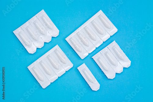 White suppositories for anal or vaginal use on blue background. Medical candles for treatment of Candida  thrush  hemorrhoids  inflammation and fever. Effective drug for timely treatment of diseases