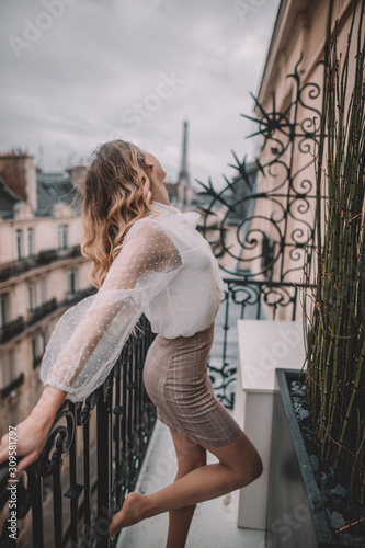 Young woman with blonde hair on Paris balcony in front of Eiffel Tower