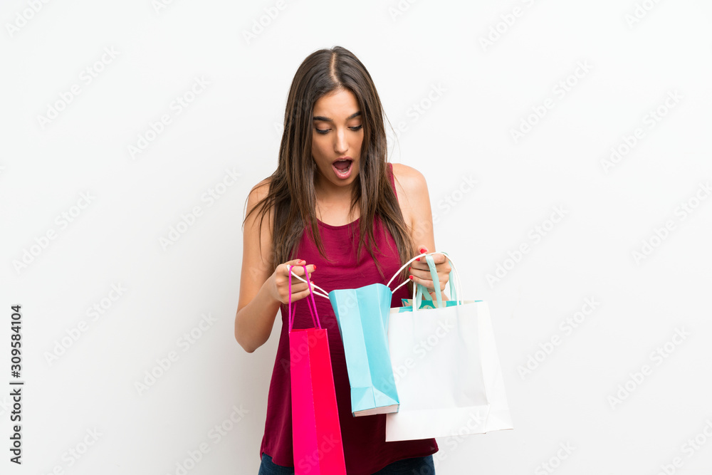 Young woman over isolated white background holding a lot of shopping bags Young woman over isolated white background holding a lot of shopping bags