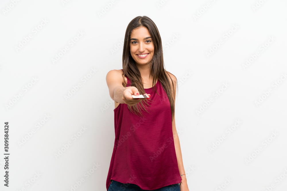 Young woman over isolated white background holding a credit card