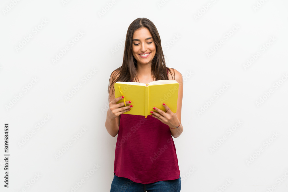 Young woman over isolated white background holding and reading a book Young woman over isolated white background holding and reading a book