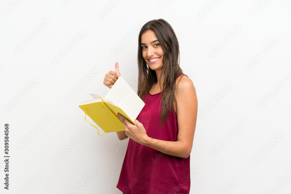 Young woman over isolated white background holding and reading a book Young woman over isolated white background holding and reading a book