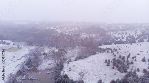 Freshly fallen snow in autumn at a rural countryside pond lined with trees
