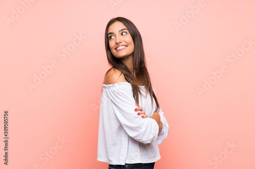 Young woman over isolated pink background with arms crossed and happy