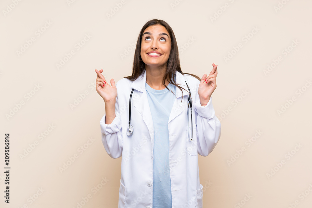 Young doctor woman over isolated background with fingers crossing Young doctor woman over isolated background with fingers crossing