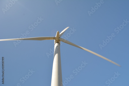 Close-up and low angle view of spinning wind turbine, providing green, low carbon and renewable electricity and energy
