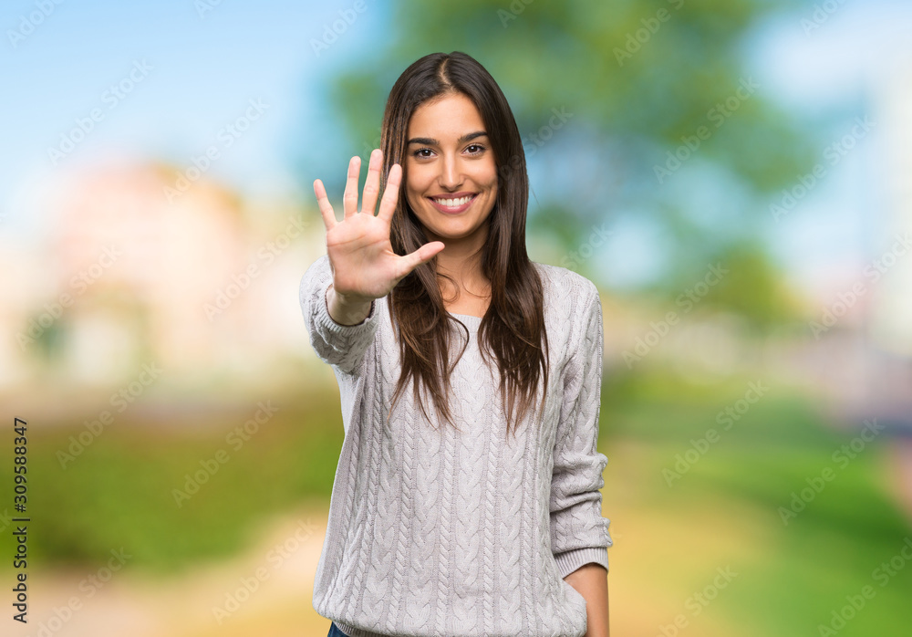 Young hispanic brunette woman counting five with fingers at outdoors