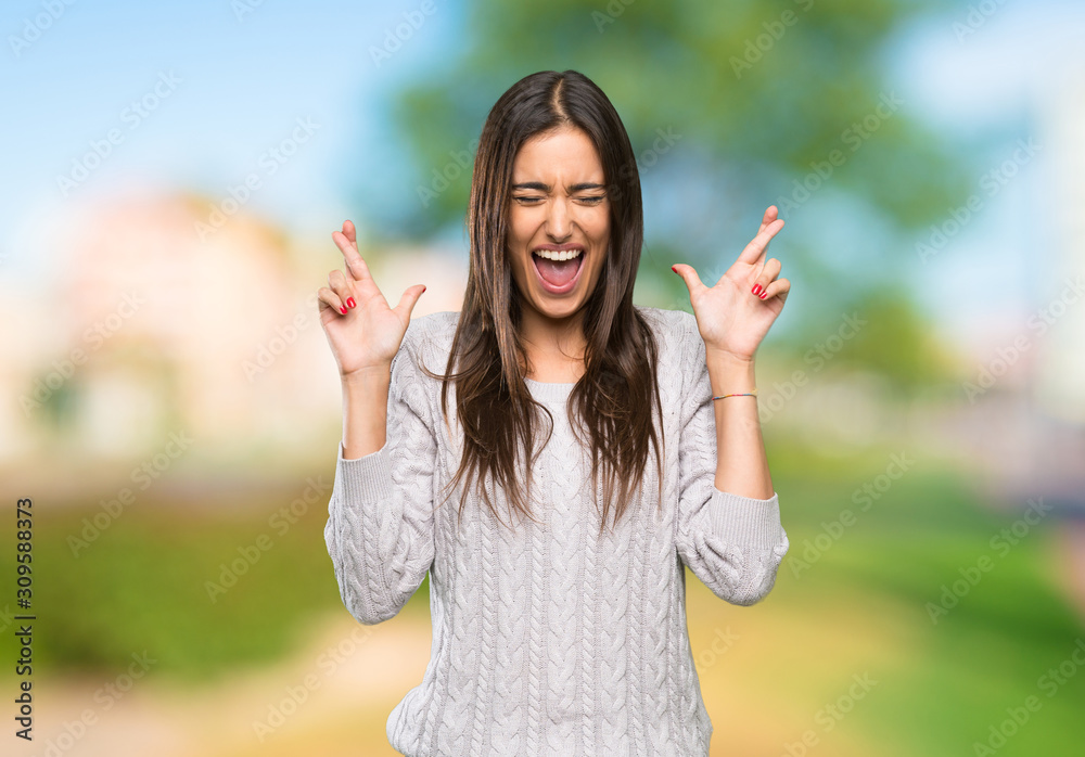 Young hispanic brunette woman with fingers crossing at outdoors Young hispanic brunette woman with fingers crossing at outdoors